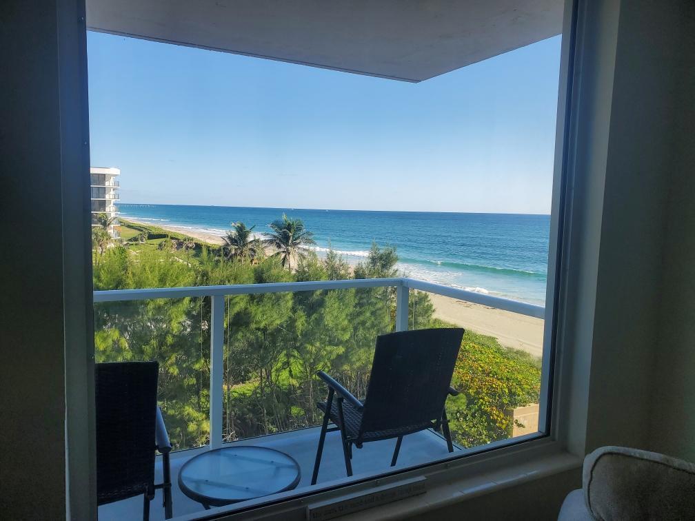A balcony with two chairs and a glass table overlooks a beach and the ocean — 3450 S Ocean Boulevard # 406, Palm Beach FL 33480, PALM BEACH, FL