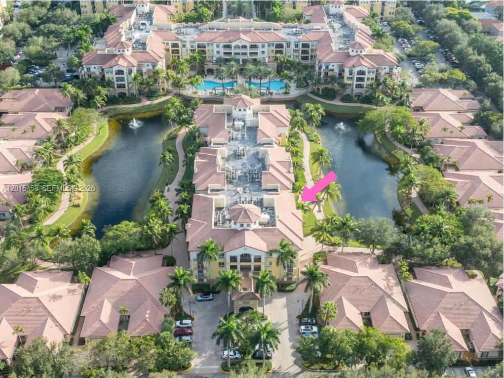 An aerial view of a multi-story residential complex featuring tiled roofs and a central lake — 16135 Emerald Estates Dr # 166, Weston FL 33331, WESTON, FL
