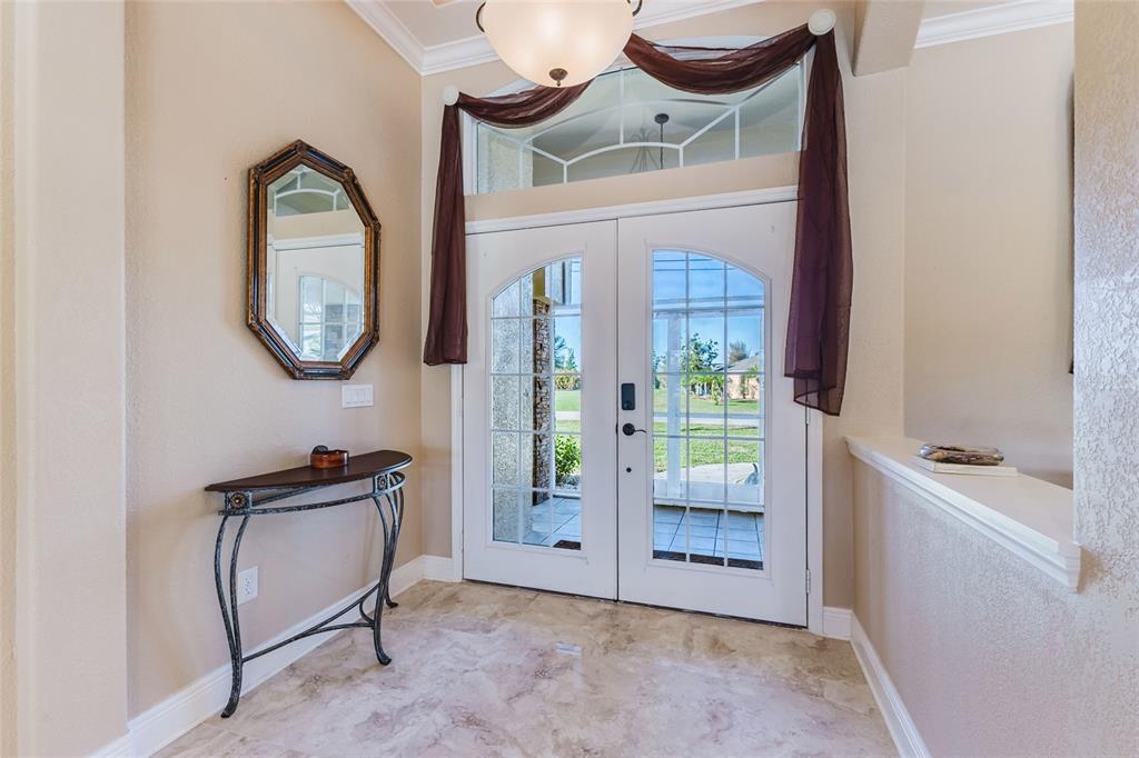 An entryway features a tile floor, a console table, a wall mirror, and double glass doors — 1900 NUREMBERG BOULEVARD, PUNTA GORDA, FL