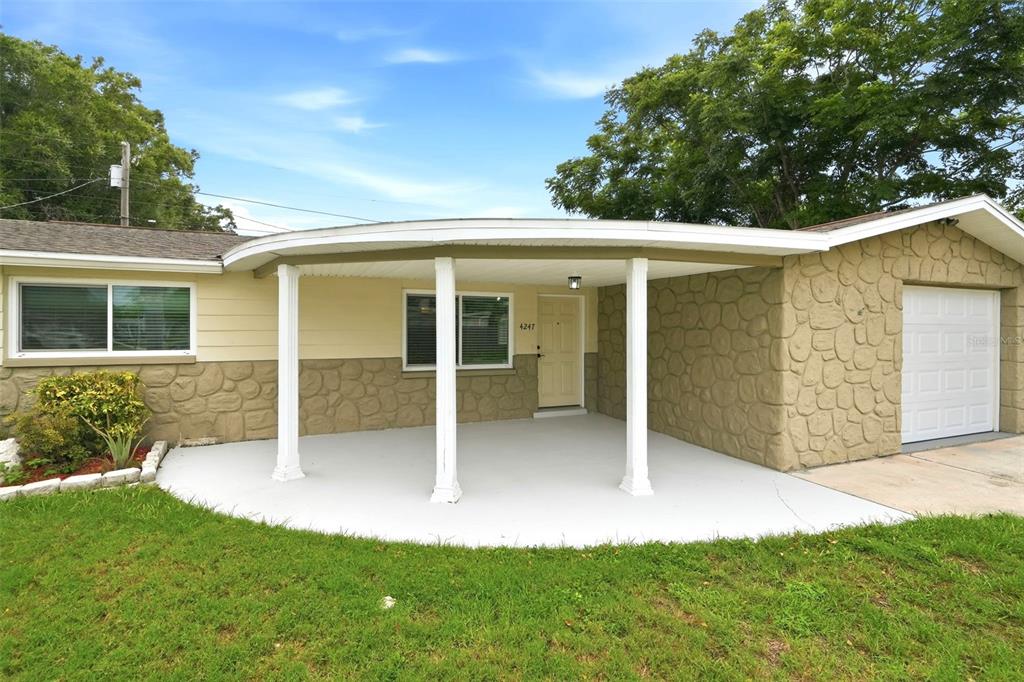 A single-story house exterior features a curved covered porch, stone siding, and a white garage — 4247 GULFSHORE COURT, NEW PORT RICHEY, FL