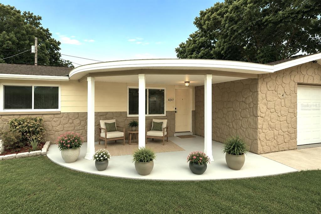 A curved front porch with white columns sits in front of a house with stone siding — 4247 GULFSHORE COURT, NEW PORT RICHEY, FL