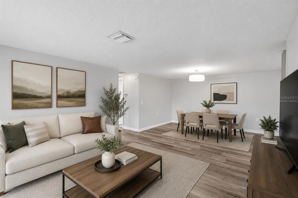 A living and dining room with wood-look flooring, neutral walls, and virtual staging — 4247 GULFSHORE COURT, NEW PORT RICHEY, FL