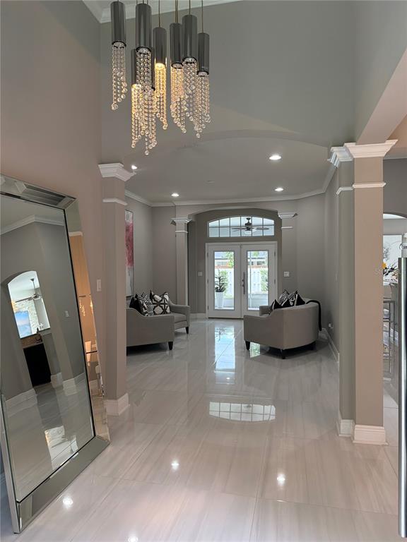 A bright foyer features a crystal chandelier, large floor mirror, and light-colored tile flooring — 10133 FACET COURT, ORLANDO, FL