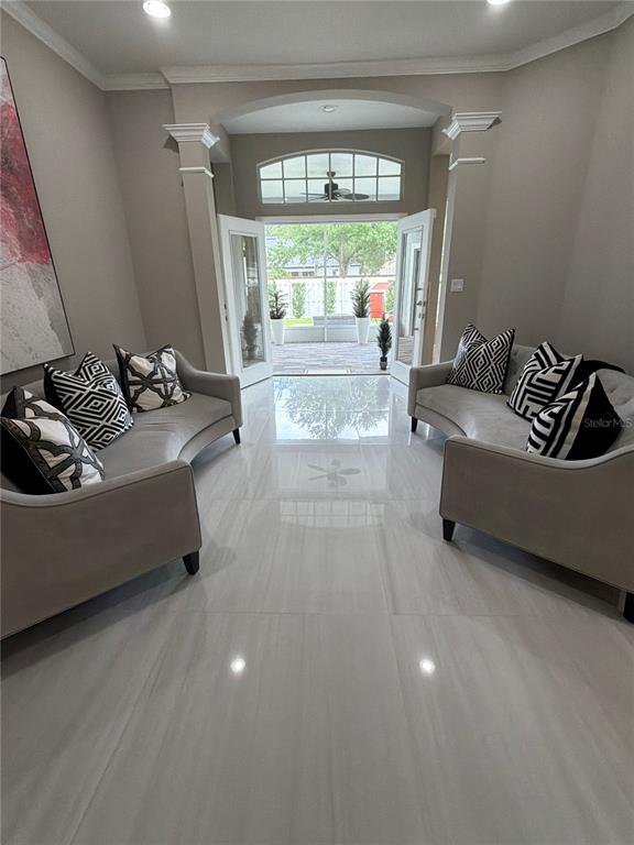 A living room with two curved sofas, tile flooring, and glass doors leading to a patio — 10133 FACET COURT, ORLANDO, FL