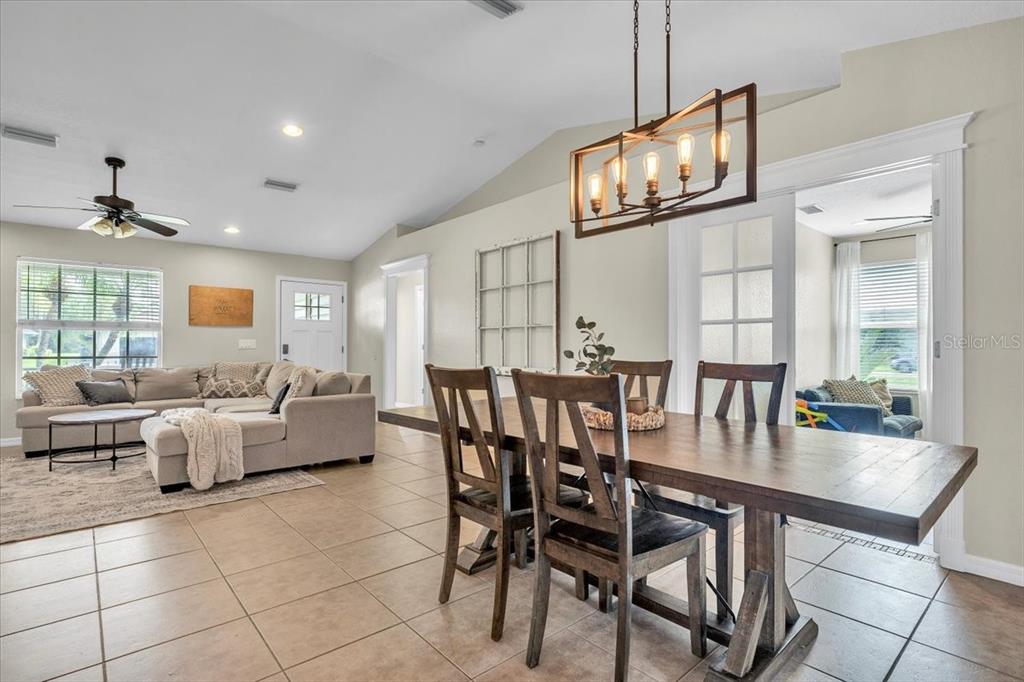 A dining area with a wooden table and chandelier sits beside a living room — 25435 AREQUIPA DRIVE, PUNTA GORDA, FL