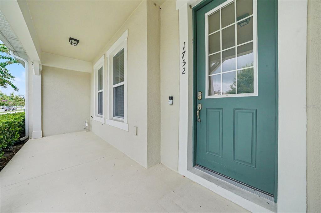 A teal front door with a window sits on a covered concrete porch — 1752 FULFILLMENT DRIVE, KISSIMMEE, FL
