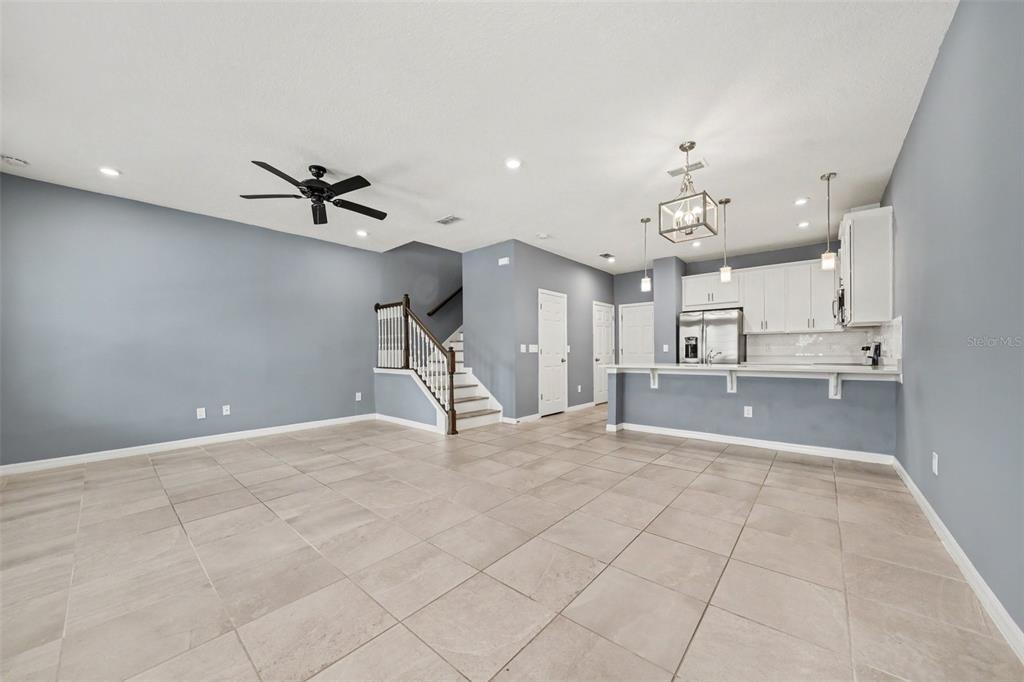 An open-concept living area features light gray walls, large floor tiles, and a kitchen island — 1752 FULFILLMENT DRIVE, KISSIMMEE, FL