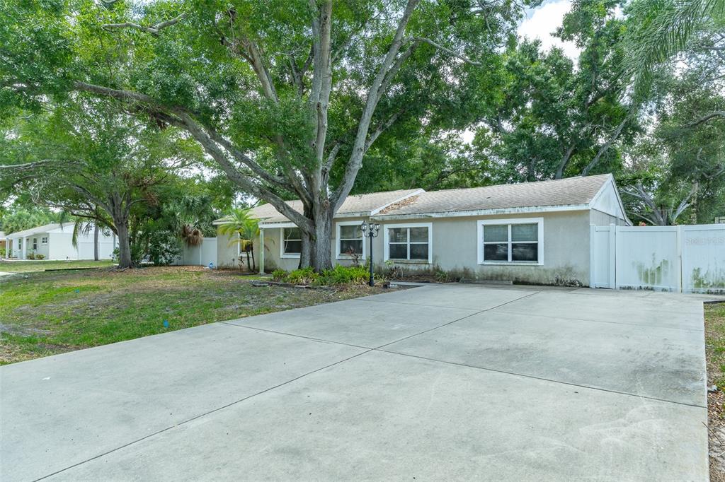 A single-story house with a concrete driveway, large shade trees, and a white fence — 4416 W ANITA BOULEVARD, TAMPA, FL