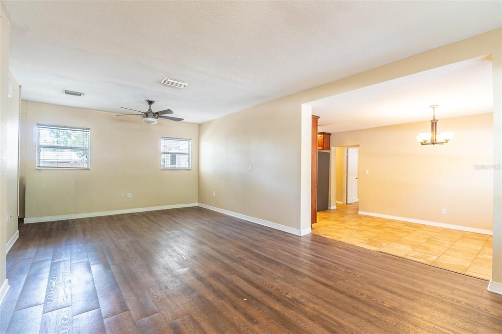 An open living area with wood-look flooring transitions into a tiled dining space — 4416 W ANITA BOULEVARD, TAMPA, FL