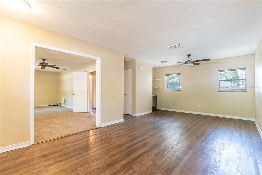A living room with wood-look flooring, a ceiling fan, and an opening to a carpeted room — 4416 W ANITA BOULEVARD, TAMPA, FL