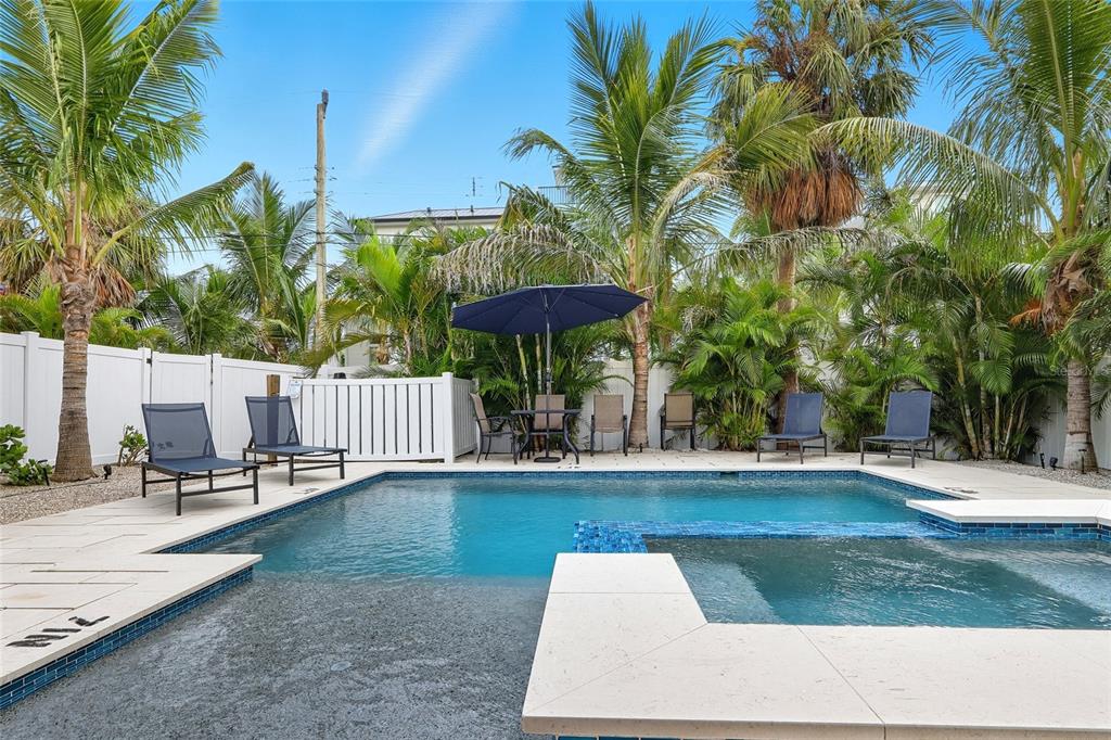 A backyard swimming pool with a spa, lounge chairs, and patio furniture under palm trees — 3016 GULF DRIVE, HOLMES BEACH, FL