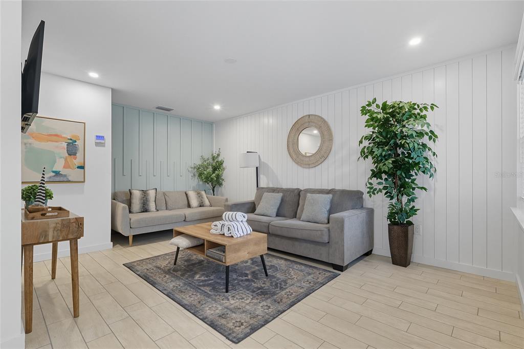 A living room features two gray sofas, a wood coffee table, and white paneled walls — 3016 GULF DRIVE, HOLMES BEACH, FL