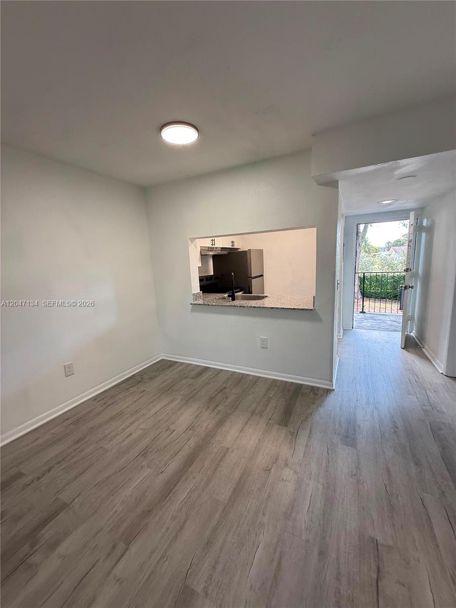 A dining area with wood-look flooring features a kitchen pass-through window and a balcony door — 1220 NW 103rd Ln # 413, Miami FL 33147, MIAMI, FL