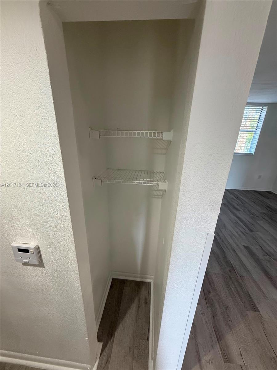 A narrow closet features two white wire shelves against white walls and wood-look flooring — 1220 NW 103rd Ln # 413, Miami FL 33147, MIAMI, FL