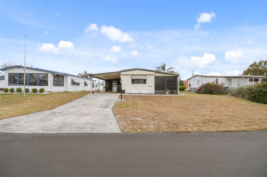 A single-story manufactured home with a concrete driveway and a covered carport — 313 MONROE DRIVE, LAKELAND, FL
