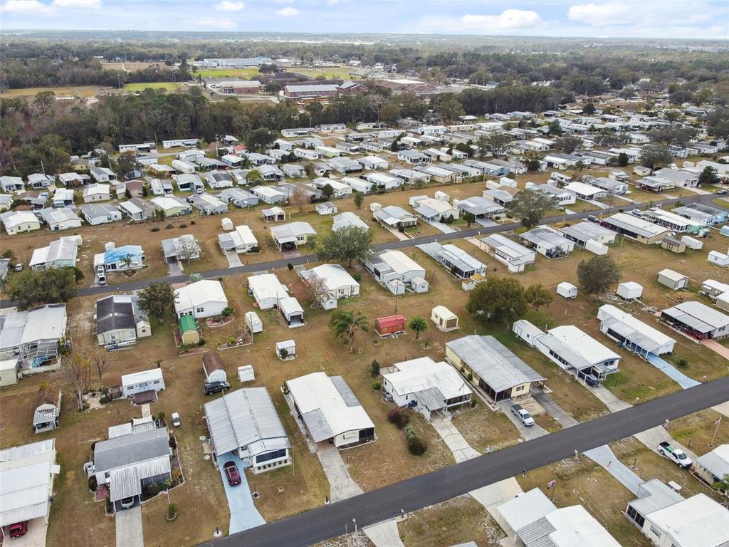 An aerial view of a mobile home community with numerous houses, driveways, and surrounding trees — 313 MONROE DRIVE, LAKELAND, FL