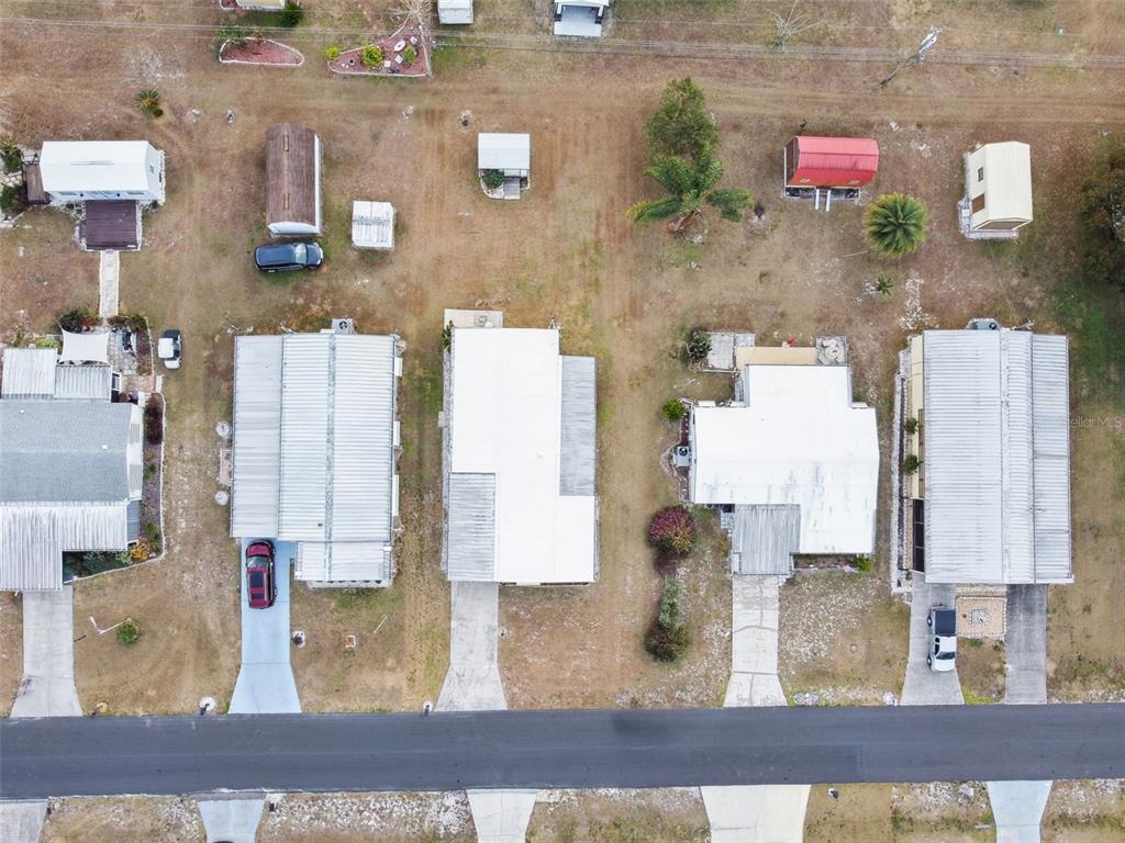 An aerial view shows several mobile homes with metal roofs and driveways along a road — 313 MONROE DRIVE, LAKELAND, FL