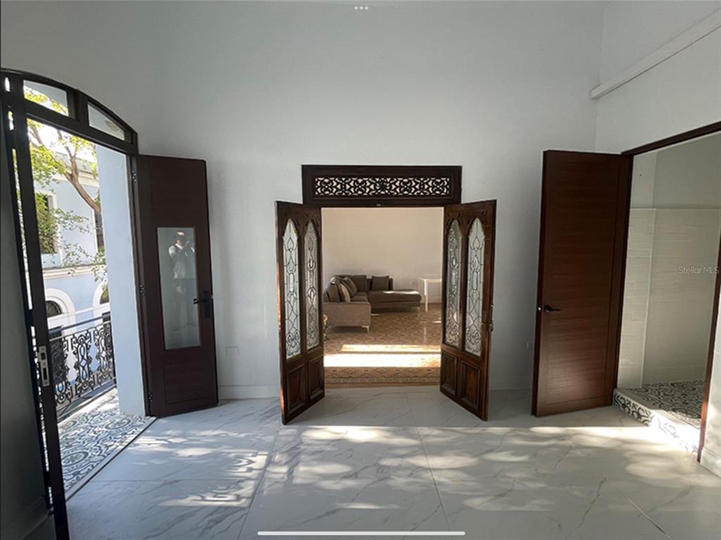 A room with white marble floors, a balcony door, and an ornate wooden doorway — 9 DEL MERCADO UNIT 2, SAN JUAN, PR