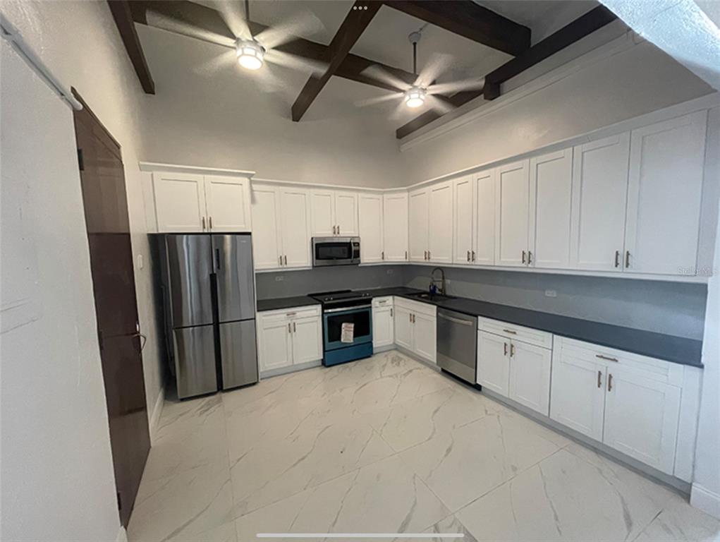 A kitchen features white cabinets, stainless steel appliances, dark countertops, and a marble-patterned tile floor — 9 DEL MERCADO UNIT 2, SAN JUAN, PR