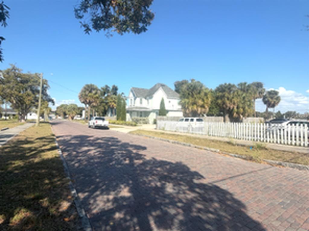A white house sits behind a white picket fence on a brick-paved residential street — 1802 N MITCHELL AVENUE, TAMPA, FL
