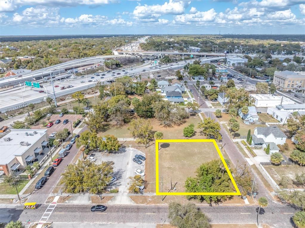 An aerial view shows a vacant rectangular lot outlined in yellow near a highway interchange — 1802 N MITCHELL AVENUE, TAMPA, FL