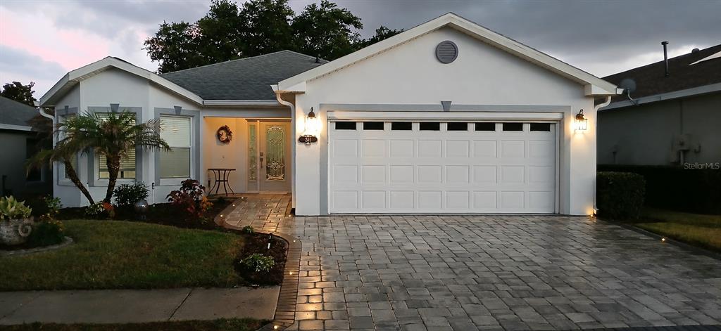 A single-story house features a white stucco exterior, a paver driveway, and a two-car garage — 241 LOURDES STREET, LAKE WALES, FL