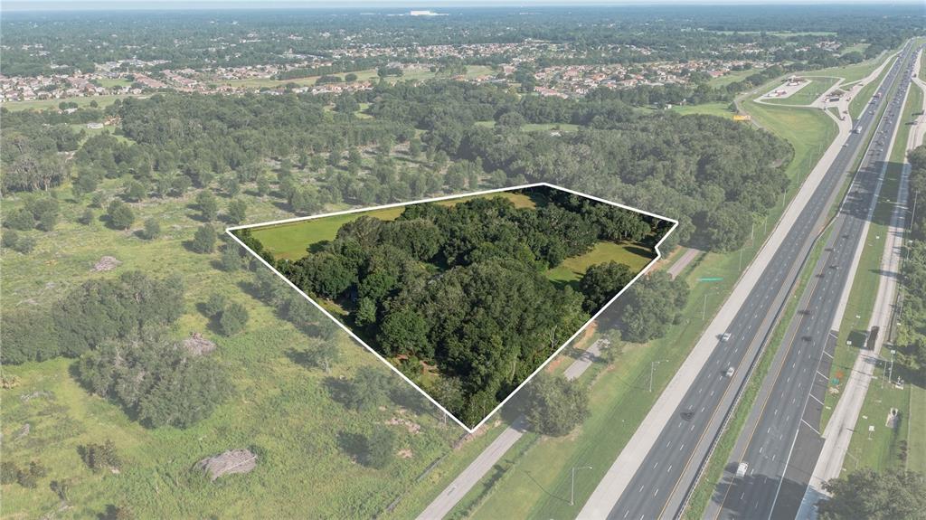 An aerial view shows a wooded property outlined in white next to a multi-lane highway — 16250 SW 20TH AVENUE ROAD, OCALA, FL