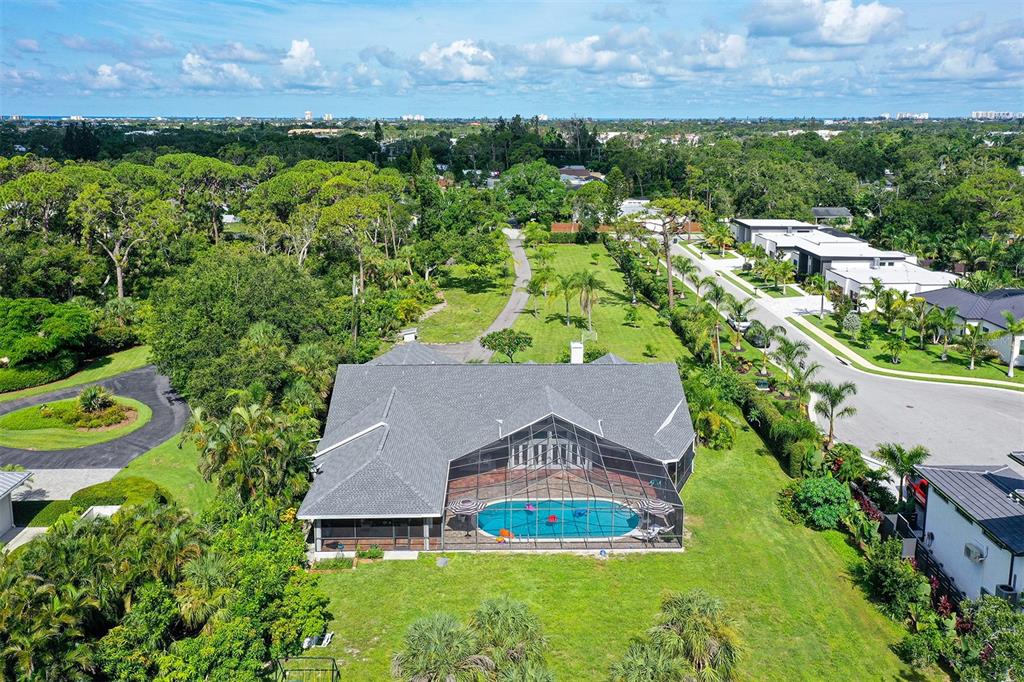 An aerial view of a house with a screened-in pool and a large grassy yard — 4935 RIVERWOOD AVENUE, SARASOTA, FL