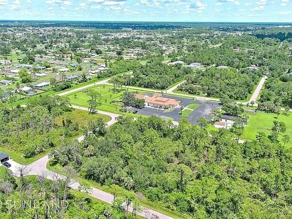 This aerial view shows a commercial building surrounded by trees and residential neighborhoods — 56 MORDECAL STREET, PORT CHARLOTTE, FL