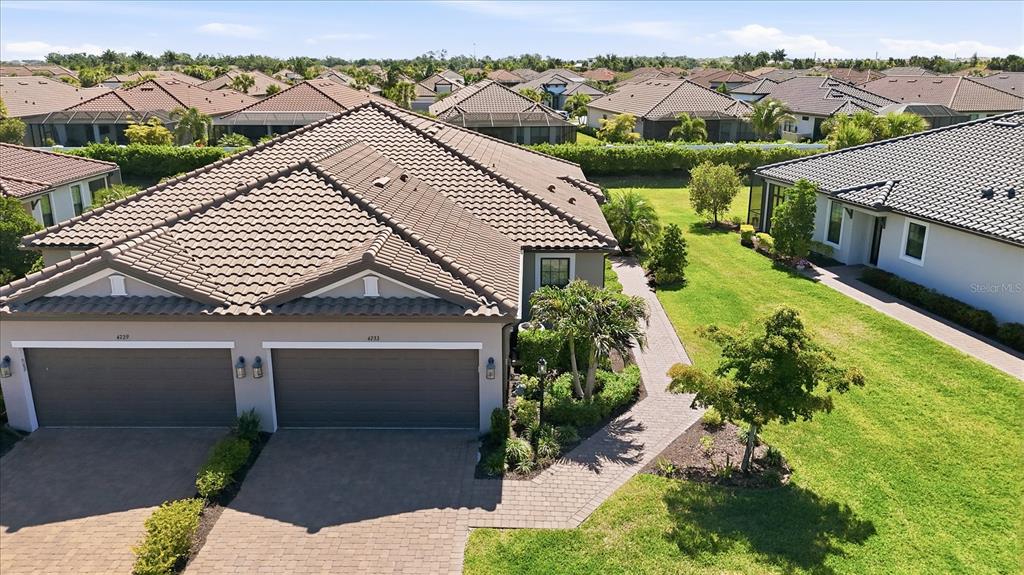 An aerial view shows the front exterior of a duplex home with a tiled roof — 4733 TORTONA COURT, BRADENTON, FL