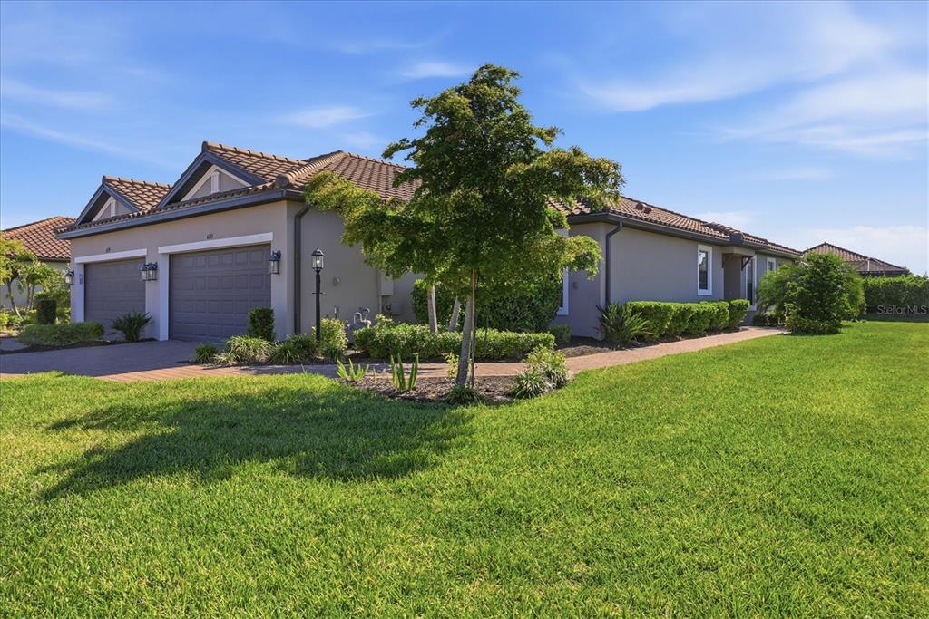 A single-story house with a two-car garage, tile roof, and a manicured front lawn — 4733 TORTONA COURT, BRADENTON, FL