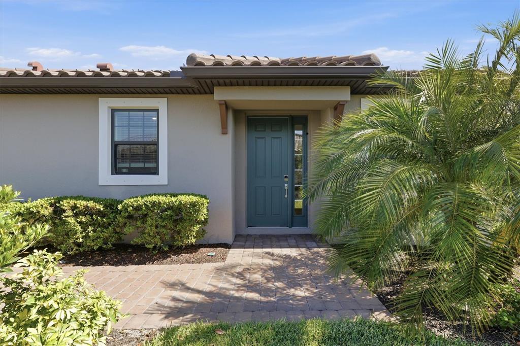 A front exterior view showing a teal door, a window, and a palm tree — 4733 TORTONA COURT, BRADENTON, FL