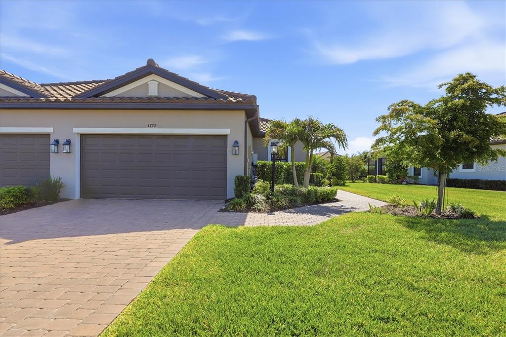 A single-story house with a brown garage door, a paved driveway, and a grassy lawn — 4733 TORTONA COURT, BRADENTON, FL