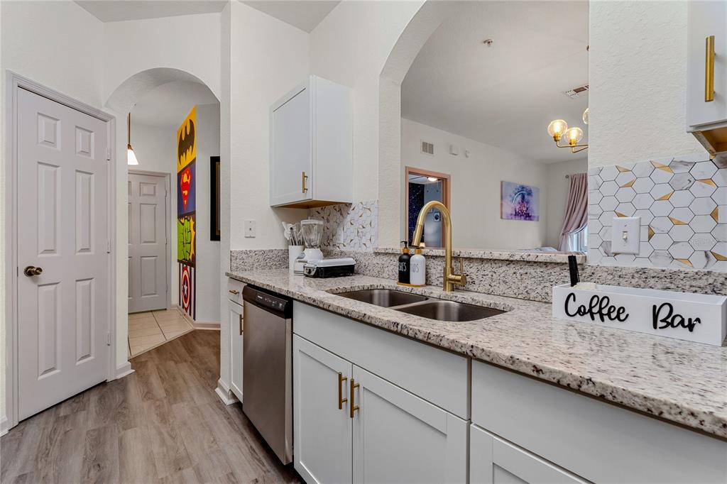 A kitchen features white cabinets, granite countertops, a stainless steel dishwasher, and a coffee bar — 2774 ALMATON LOOP UNIT 202, KISSIMMEE, FL