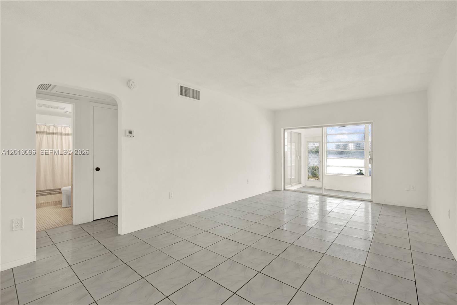 An empty room with white walls, gray tile flooring, and a sliding glass door — 285 NE 191st St # 2911, Miami FL 33179, MIAMI, FL