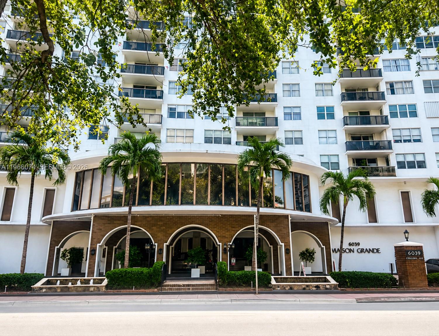 The exterior of a white multi-story apartment building features arched entrances and palm trees — 6039 Collins Ave # 1625, Miami Beach FL 33140, MIAMI BEACH, FL