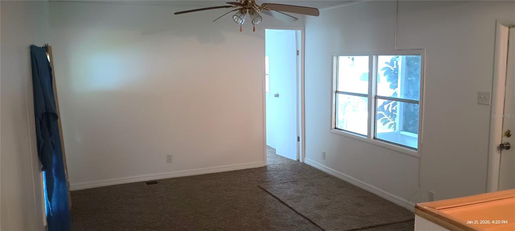 A carpeted room features a ceiling fan, a doorway, and a window overlooking a porch — 5321 CHRISTIANCY AVENUE, PORT ORANGE, FL