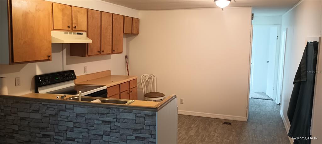 A kitchen with wood cabinets, a stone-patterned breakfast bar, and a white stove — 5321 CHRISTIANCY AVENUE, PORT ORANGE, FL