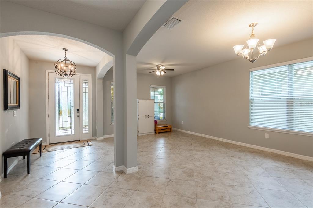 An entryway with a bench leads into a tiled dining area featuring two chandeliers — 11862 LAKE LUCAYA DRIVE, RIVERVIEW, FL