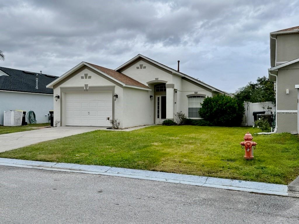 A single-story house with a white stucco exterior, a two-car garage, and a front lawn — 131 SONJA CIRCLE, DAVENPORT, FL