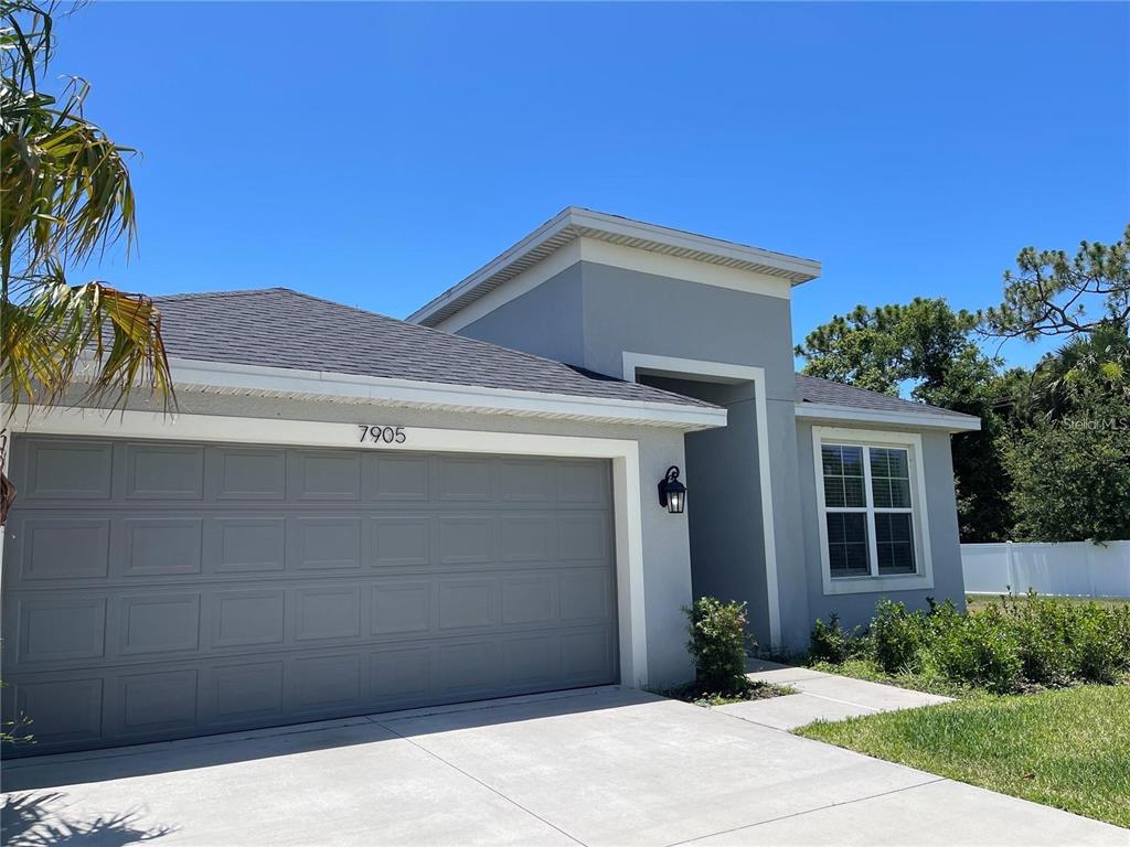 A gray single-story house features a two-car garage, a flat roof section, and a window — 7905 SILVER CLOVER COURT, RIVERVIEW, FL