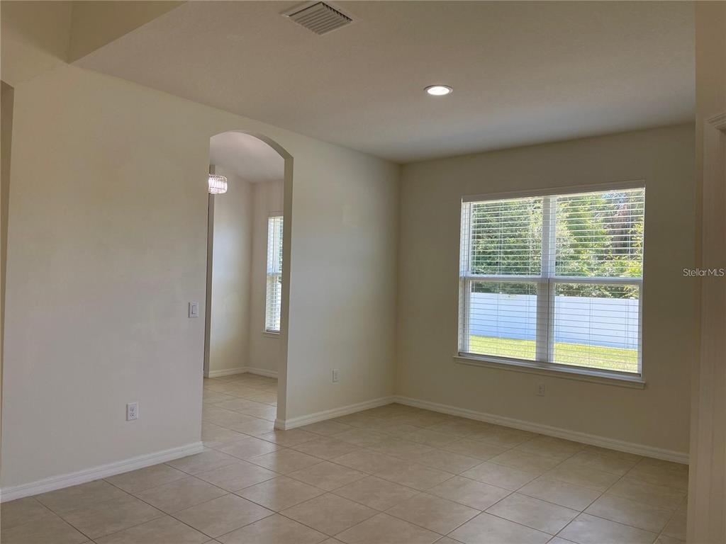 An empty room with beige tile flooring, an arched doorway, and a large window — 7905 SILVER CLOVER COURT, RIVERVIEW, FL