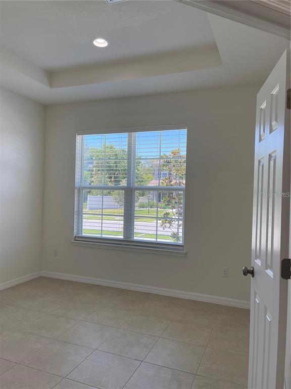 An empty room with light-colored tile flooring, a tray ceiling, and a window with blinds — 7905 SILVER CLOVER COURT, RIVERVIEW, FL