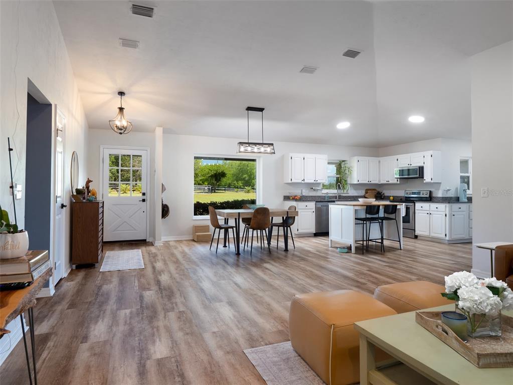 An open-concept kitchen and dining area features white cabinetry, a center island, and wood-look flooring — 23053 NW 142ND AVENUE, HIGH SPRINGS, FL