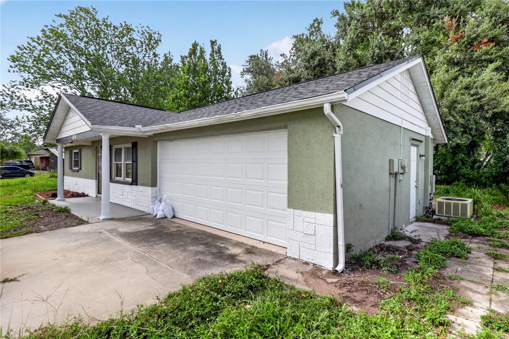 A single-story house with a green stucco exterior, white trim, and an attached two-car garage — 7036 ASHWOOD DRIVE, PORT RICHEY, FL