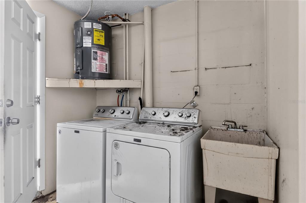 A laundry room features a washer, dryer, utility sink, and a water heater on a shelf — 7036 ASHWOOD DRIVE, PORT RICHEY, FL