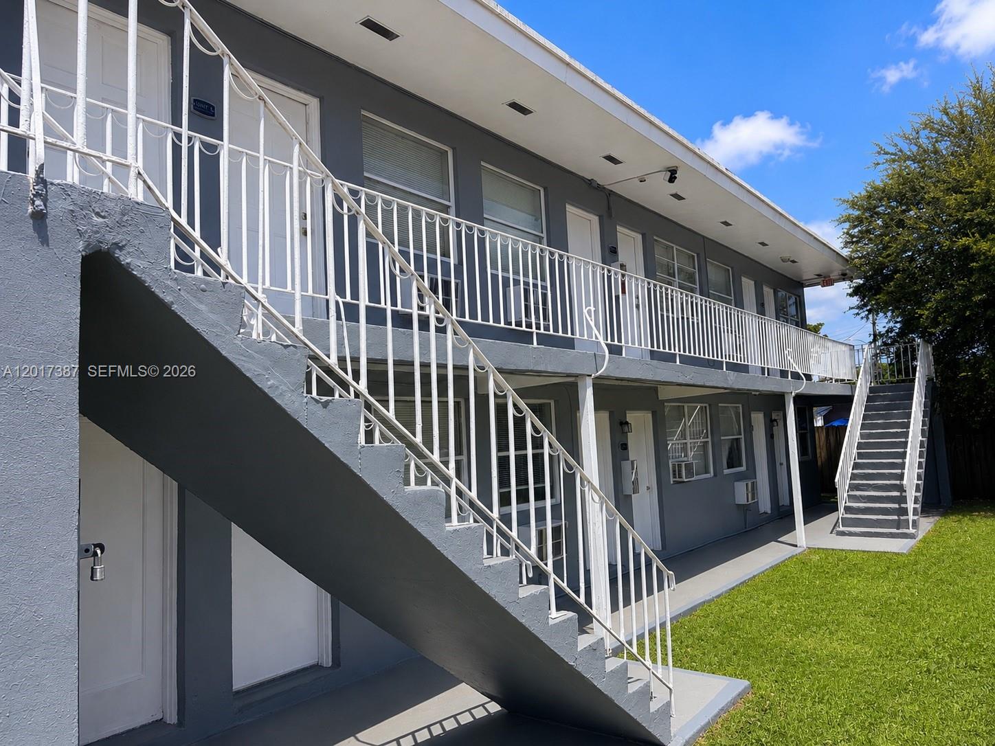 A two-story apartment building features gray exterior walls, white metal railings, and outdoor staircases — 1761 Ali Baba Ave, Opa-Locka FL 33054, OPA-LOCKA, FL
