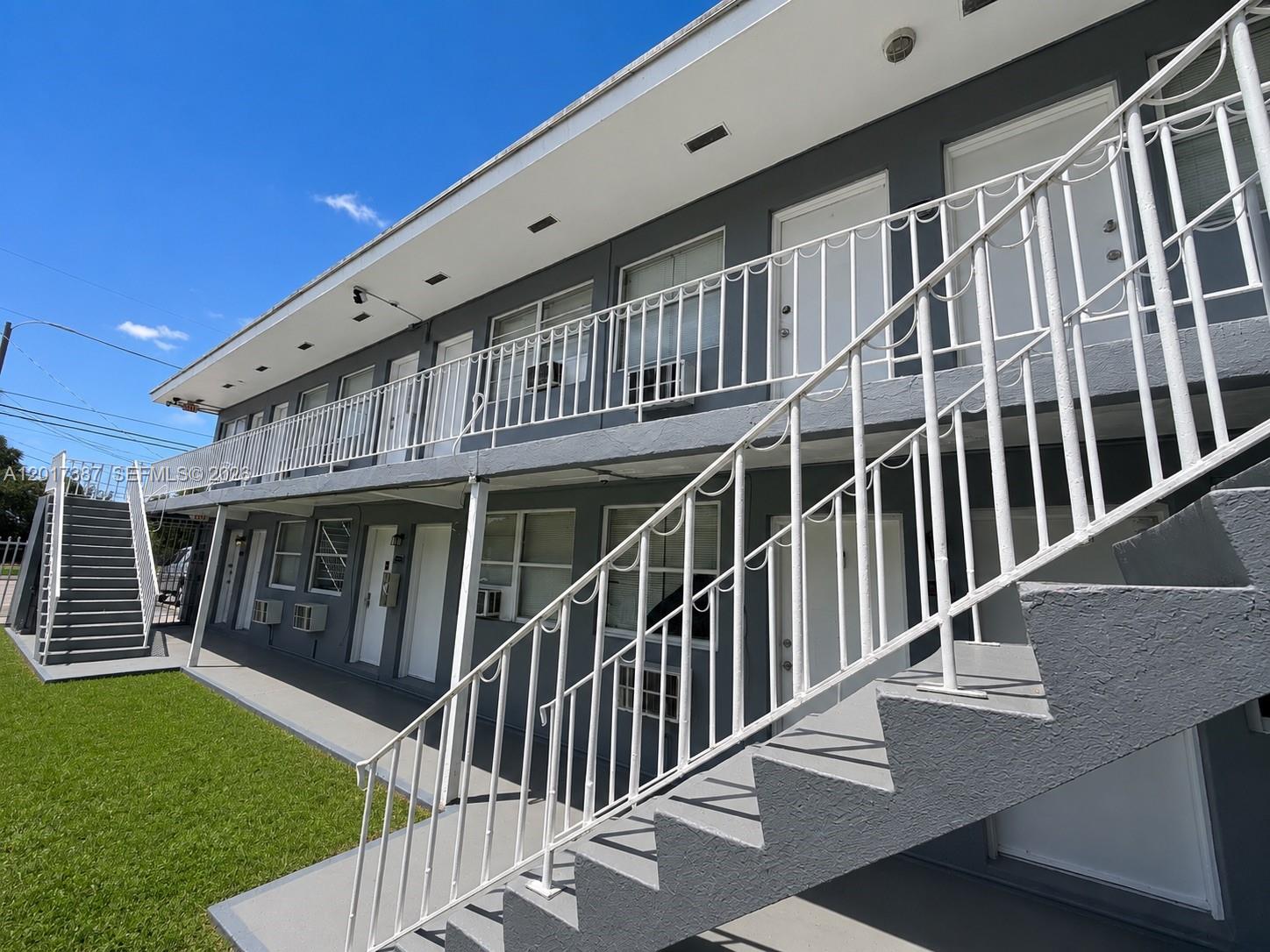 A two-story apartment building features gray exterior walls, white railings, and an outdoor staircase — 1761 Ali Baba Ave, Opa-Locka FL 33054, OPA-LOCKA, FL