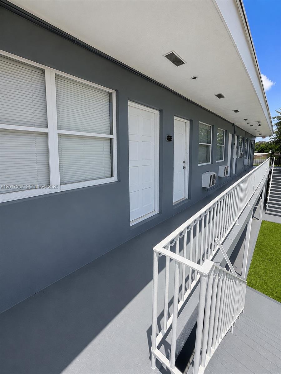 An exterior view shows a gray building with a white balcony railing and staircase — 1761 Ali Baba Ave, Opa-Locka FL 33054, OPA-LOCKA, FL