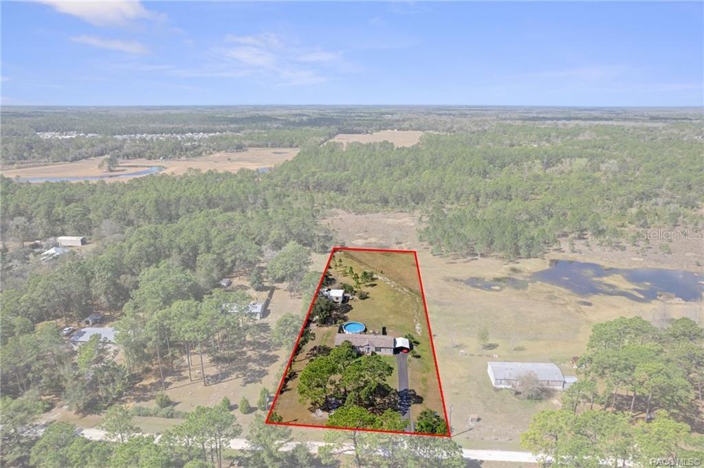 An aerial view shows a house with a pool on a large, fenced-in rural lot — 2430 S WAKULLA POINT, HOMOSASSA, FL